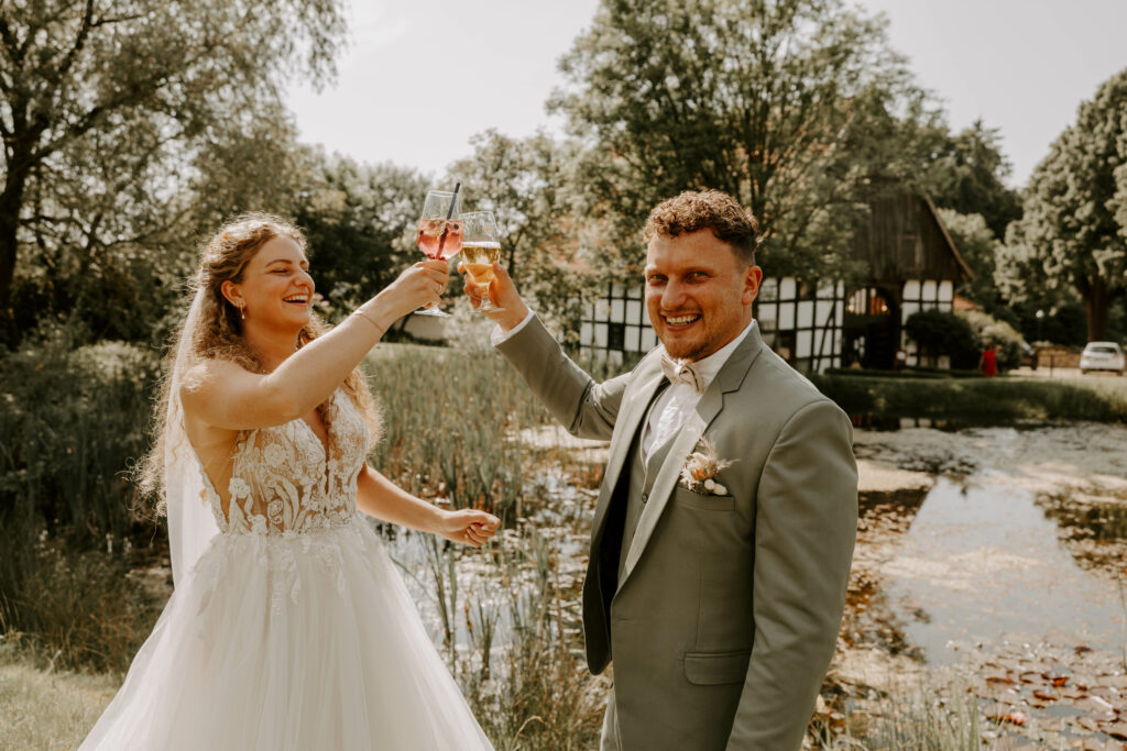 Brautpaar stoßt auf ihre Hochzeit an. Schauen glücklich in die Kamera. Partyfotos.