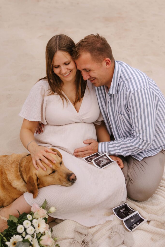 Babybauchfotoshooting mit Hund am See mit Sand und Sonnenuntergang
